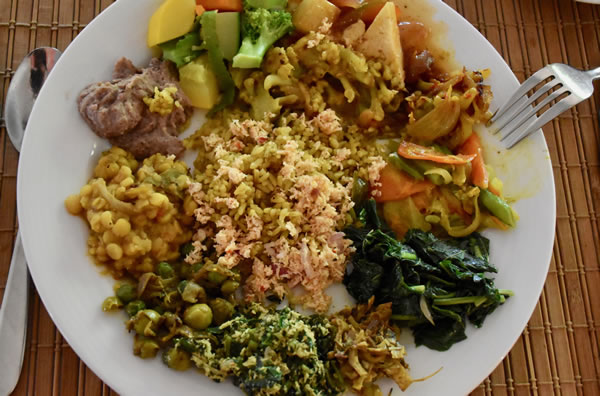 Rice and curry platter: masala rice with coconut sambol (centre) with from bottom left clockwise: konkun, thibbatu, red lentils, hummus, mixed vegetable curry, paneer in devil sauce, cauliflower curry, tempered capsicum, steamed fresh vegetables, thampala curry, banana blossom