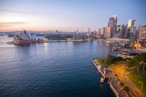 The Opera House and the skyline of Sydney, Australia on the water.