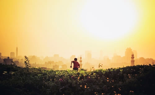 Young boy running towards his passion in a field near a city.