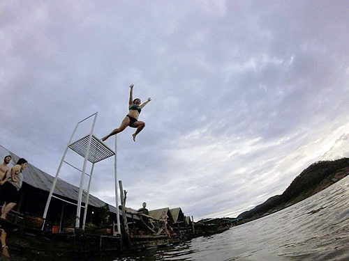 Woman diving into the ocean water the Floating Houses in Thailand.