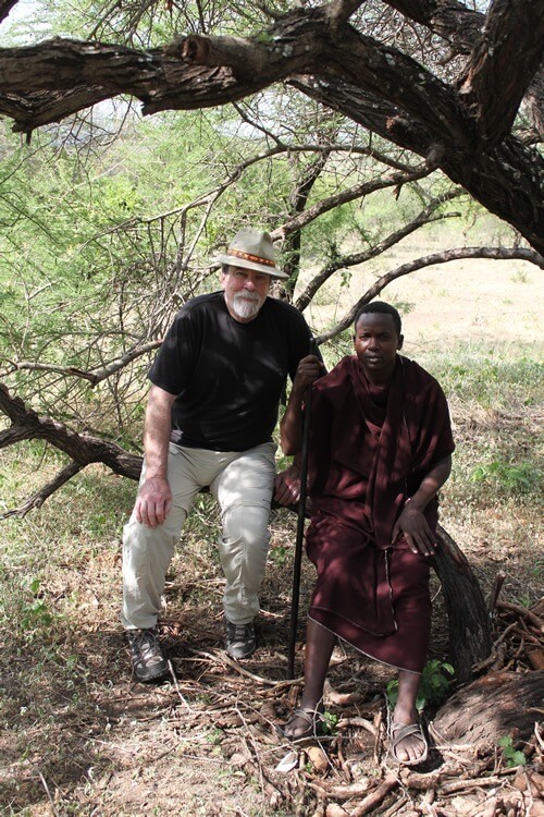 Author and Markus sit on a tree branch at a warrior camp.