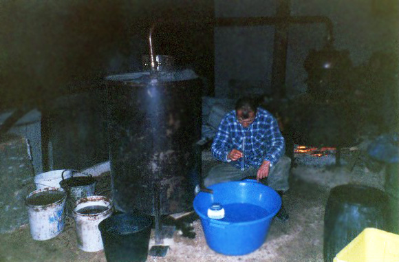 A seated Bosnian man making brandy.