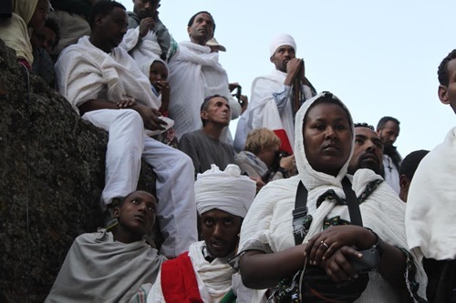 Religious members dressed in white sitting on ledges in Lalibela, Ethiopia.