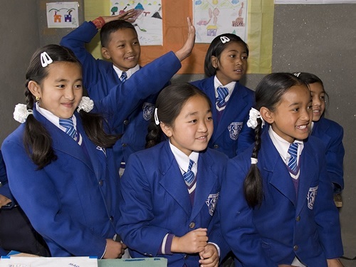 Elder children in uniform smiling in the classroom.