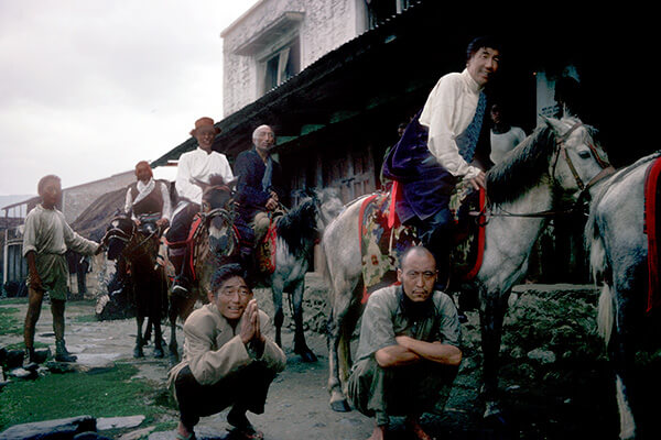 Tibetan men in Nepal on their horses and squatting.