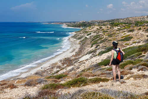 Tips for staying healthy and prepared for travel overseas, here hiking along the ocean with a backpack.