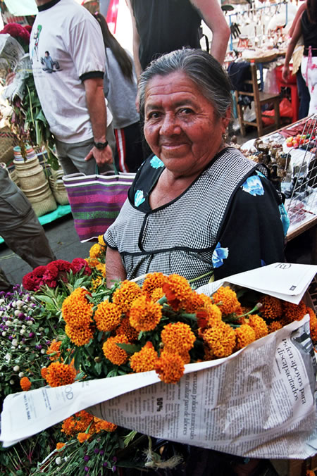 A woman named Angela with flowers at a market in Oaxaca.