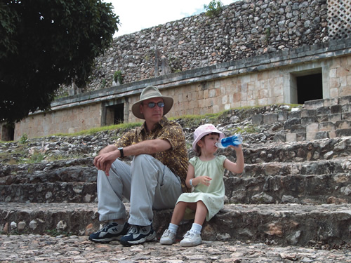 Author's daughter sitting with her father on ancient stone stairs while she drinks water.