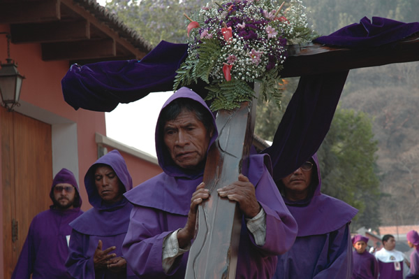 Man carrying cross dressed in blue.