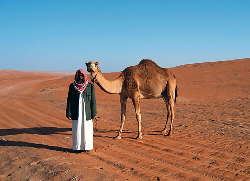 Bedouin with camel in Oman desert.