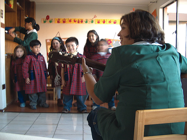 Teaching English to children and playing guitar in a classroom in Chile.