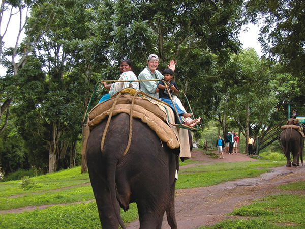 Three people riding and elephant at the Dubare Elephant Camp.