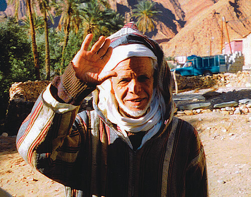 A friendly goodbye from an older Moroccan man dressed in traditional clothes.