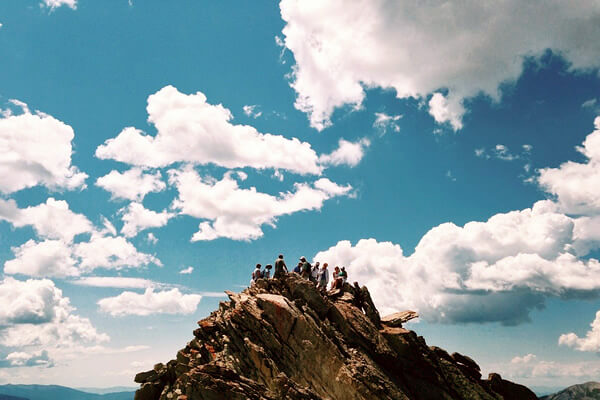 Summer teen tour as a group on top of a mountain.