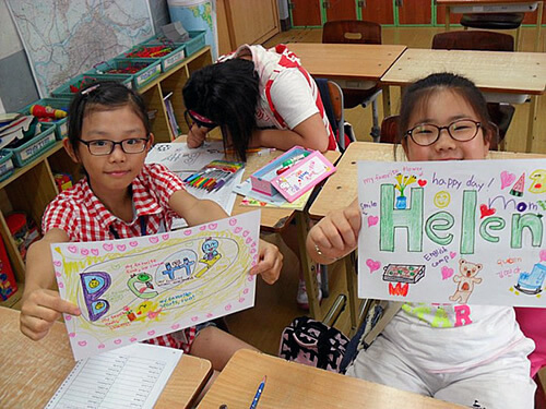Korean elementary school students choosing English names in the classroom and holding them up to show.
